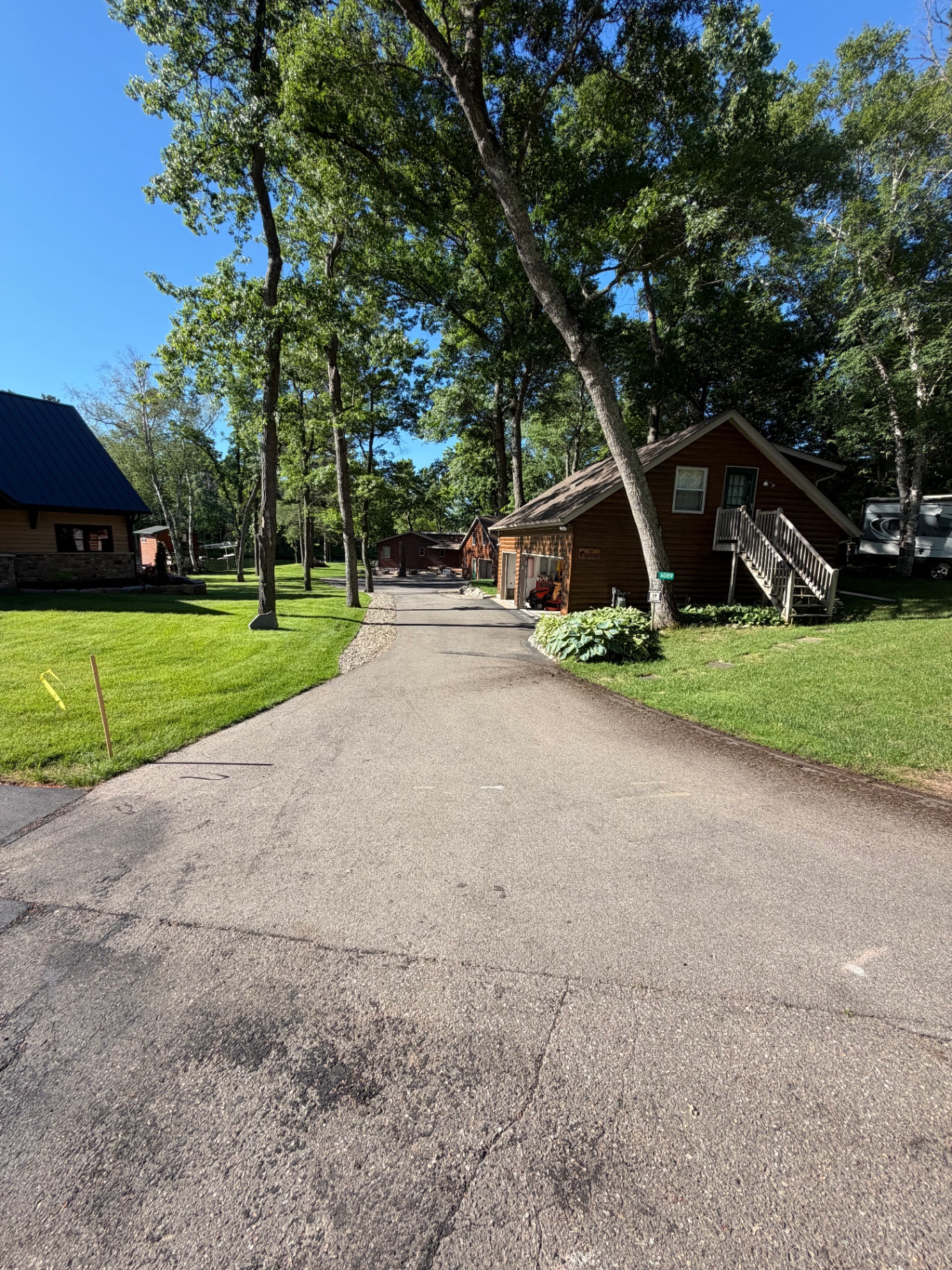 Long wooded residential driveway before sealing near cabin-style homes