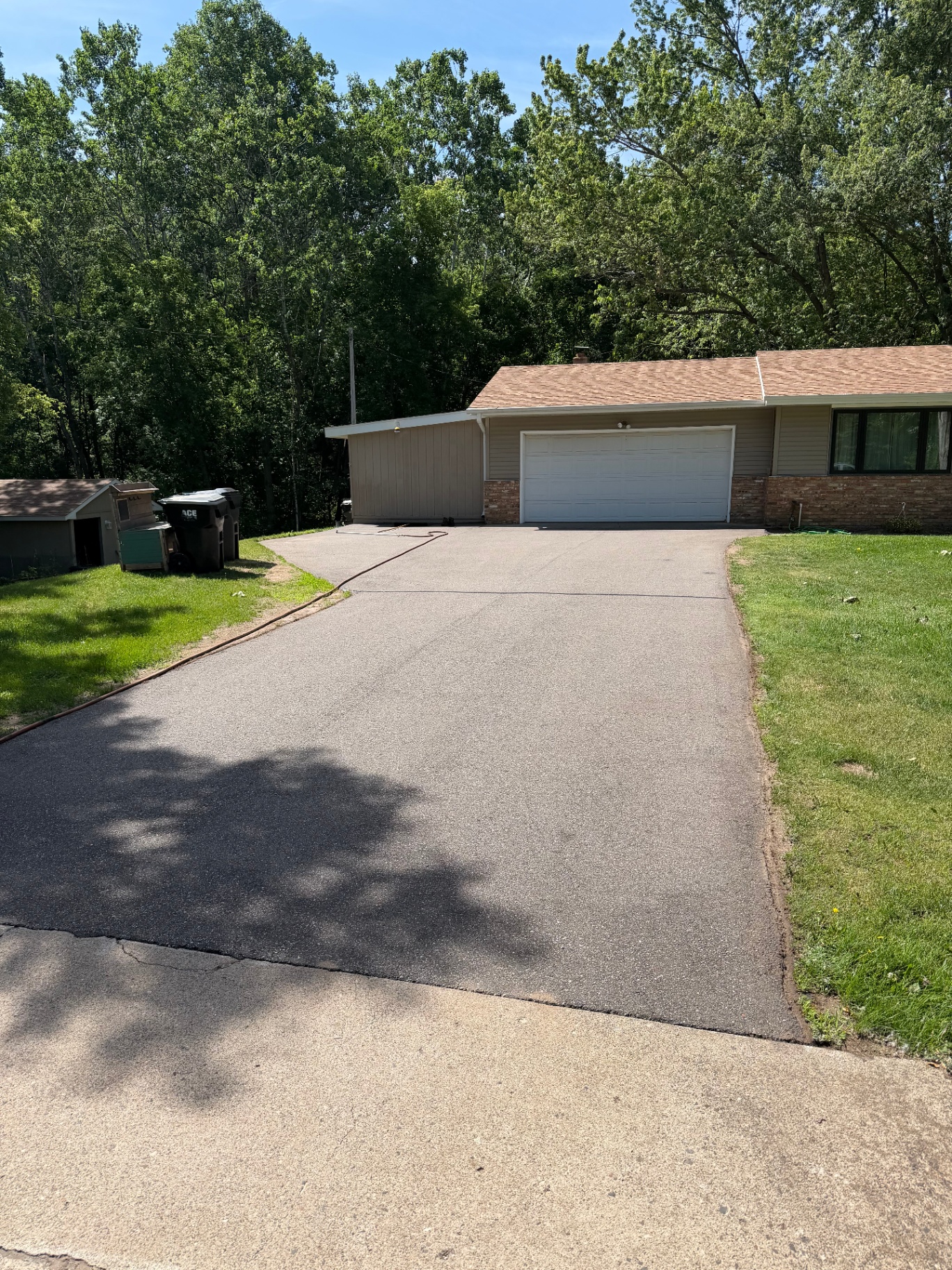 Residential driveway before seal coating with hose laid along the edge