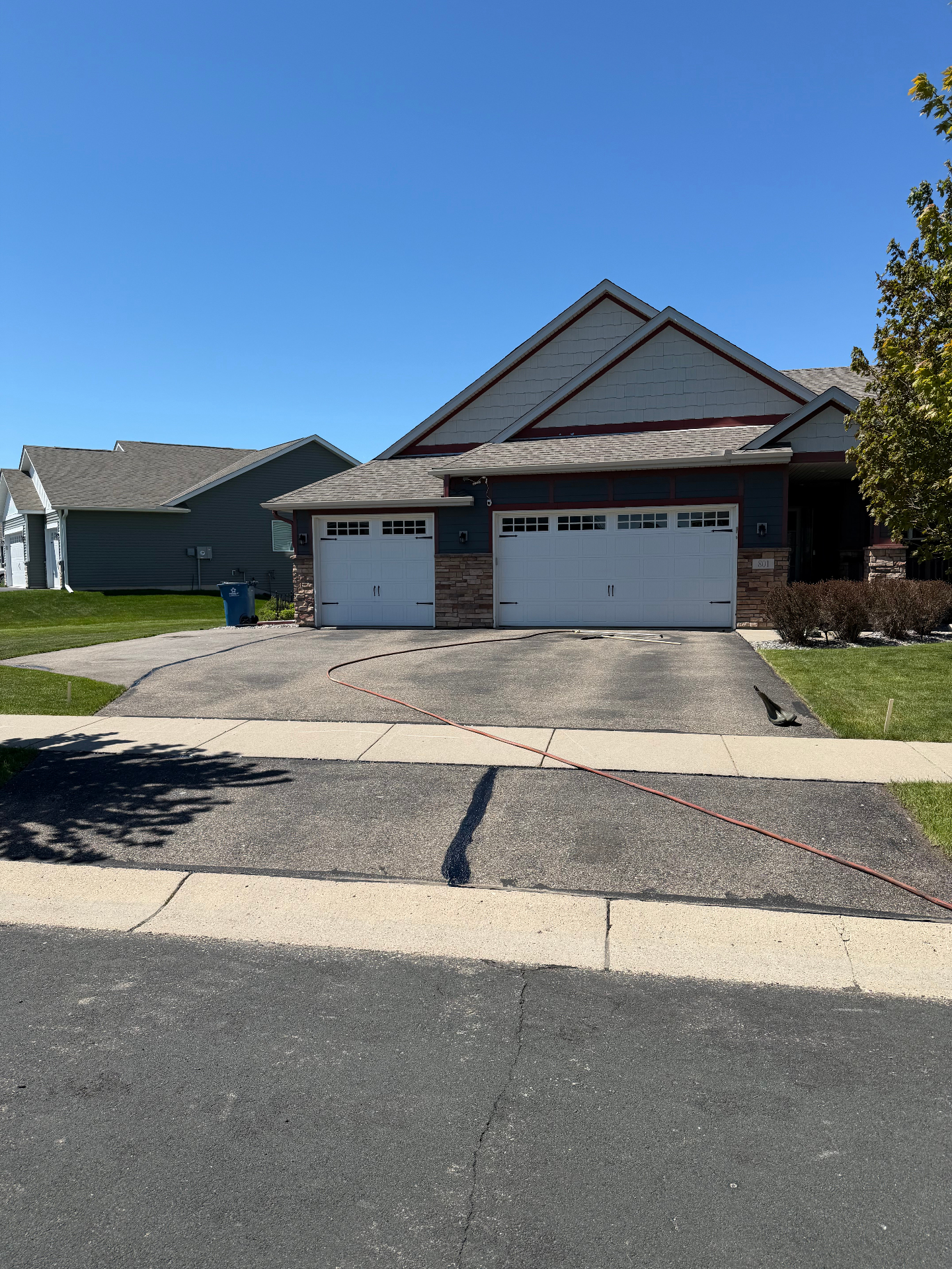 Residential driveway before seal coating with visible wear and lighter pavement tone