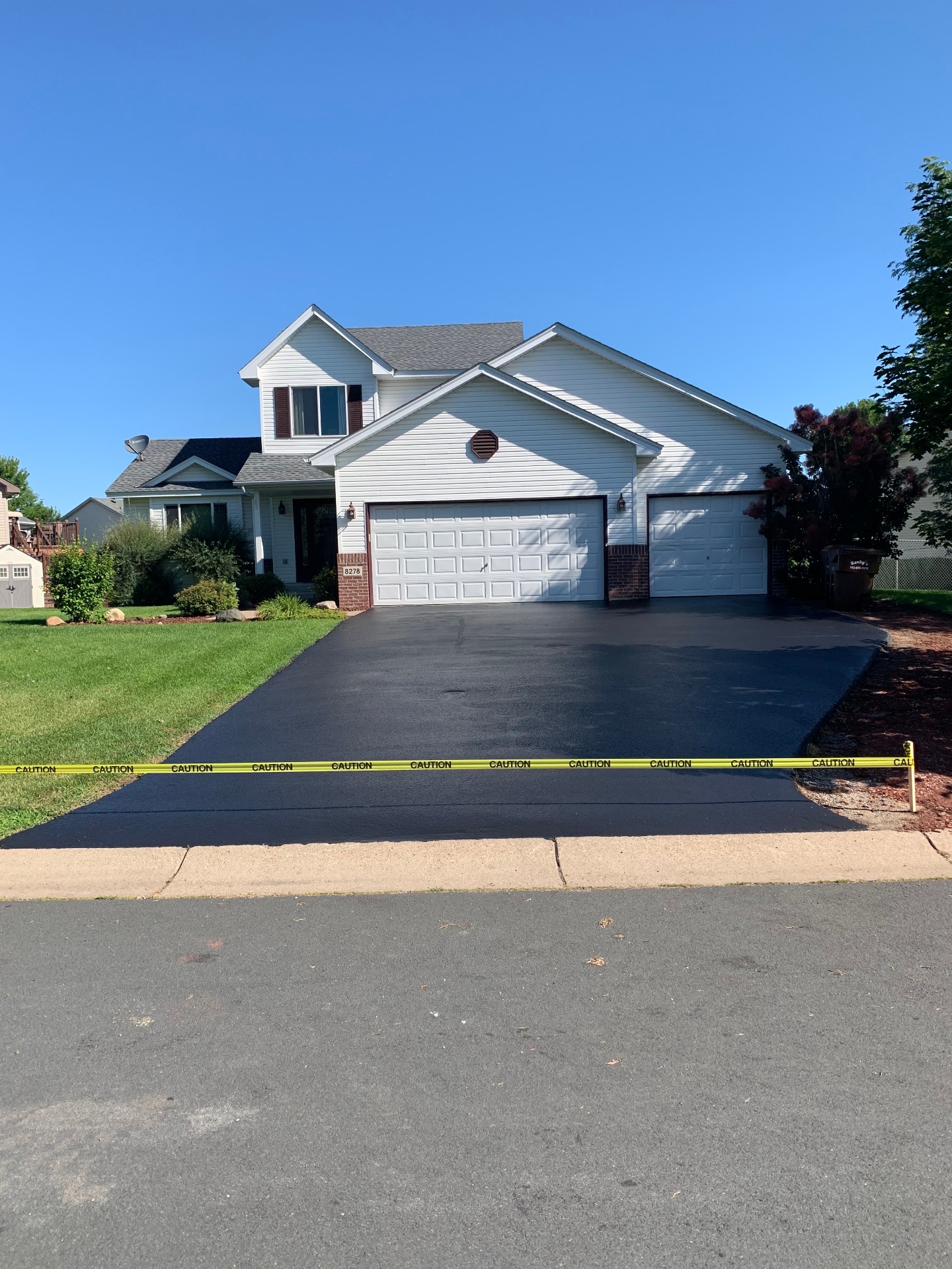 Freshly seal-coated three-car driveway with crisp edges and a uniform black finish