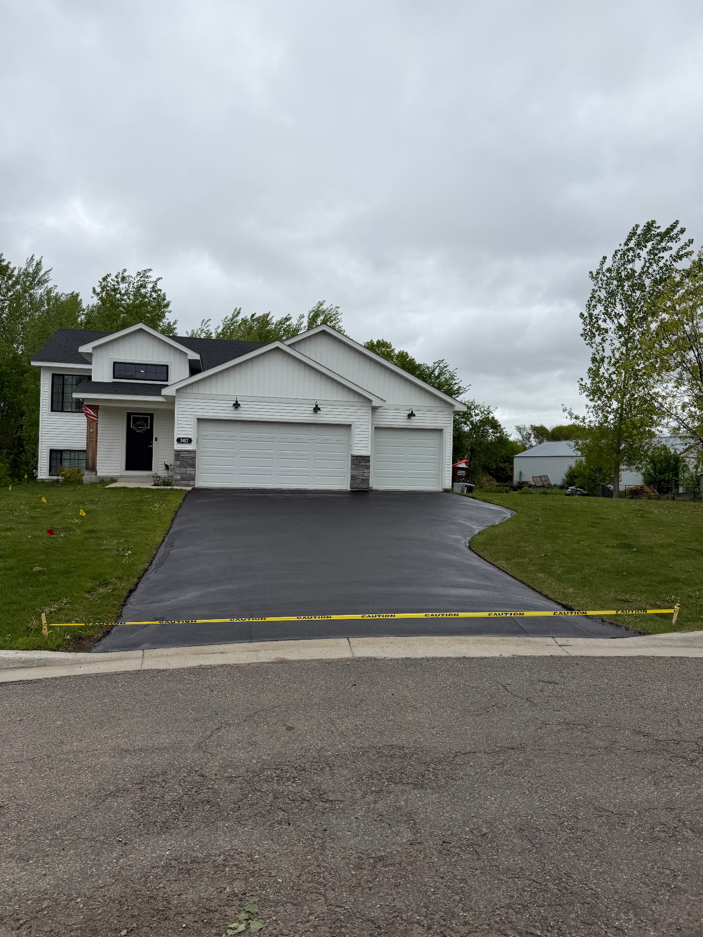 Curved black driveway in front of a white home after recent service