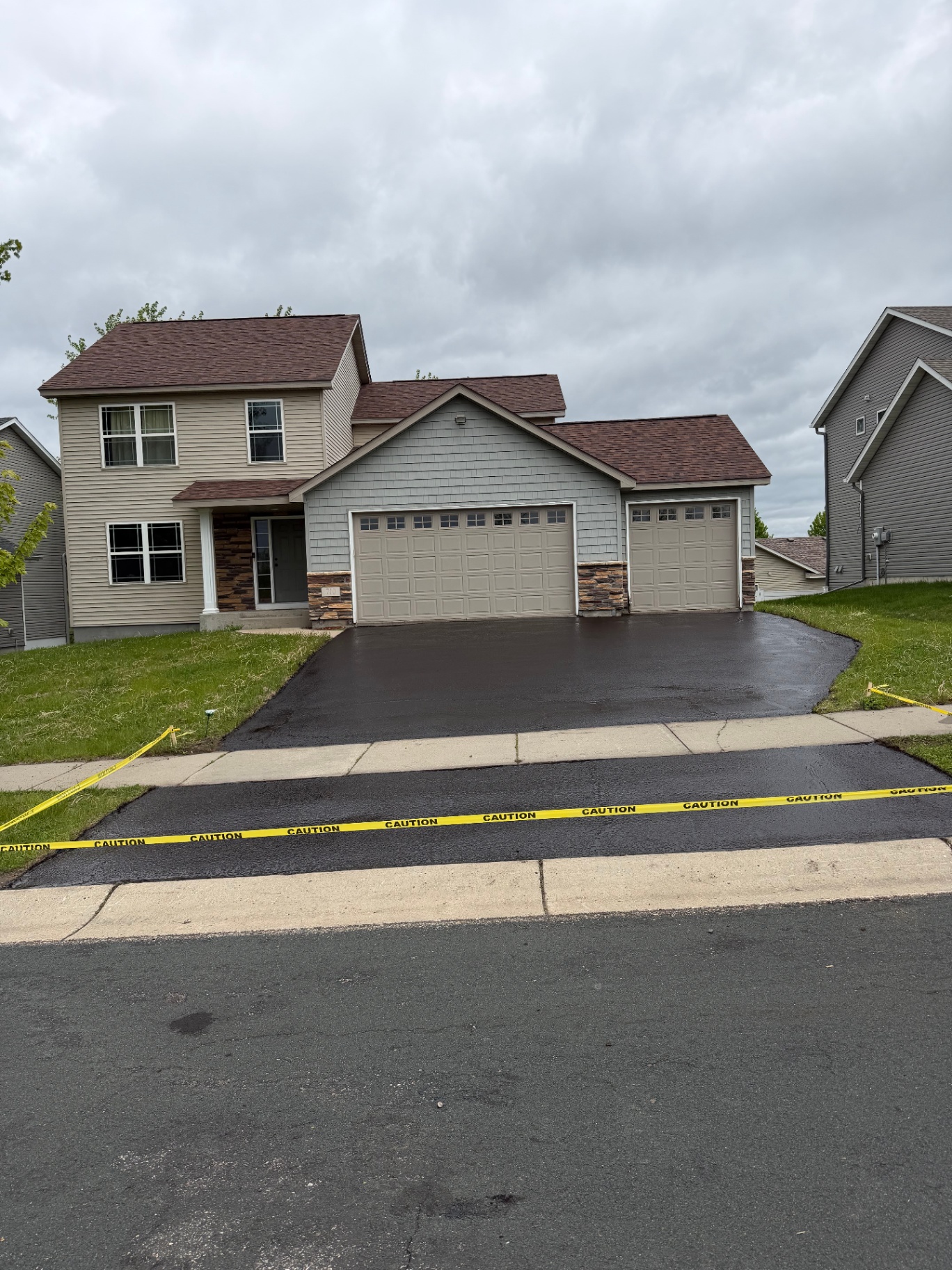 Same residential driveway after finishing with a rich black asphalt surface